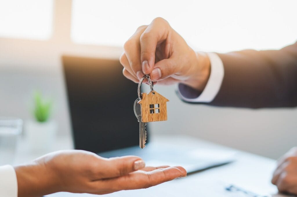 close up view hand of property realtor / landlord giving key house to buyer / tenant..